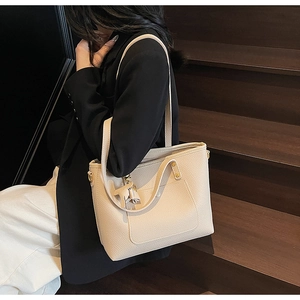 Detailed view of beige lychee texture leather tote bag with tassel and front pocket design