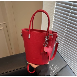 Detail of red lychee grain leather bucket bag featuring a cute elephant charm and silver hardware