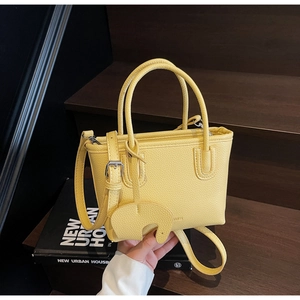 Close-up of bright yellow litchi pattern tote bag with a cute elephant charm on wooden stairs
