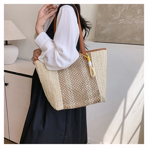 Close-up of a large woven beach tote with beige stripes and brown shoulder straps