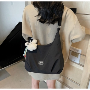 Detail of black nylon hobo bag with grid texture and white plush bear charm