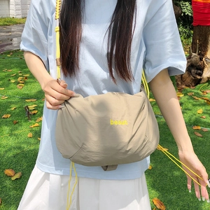 Detail view of nylon drawstring crossbody bag with yellow rope strap on grass