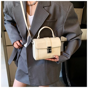 Detail view of a cream minimalist square handbag styled with a grey business casual blazer