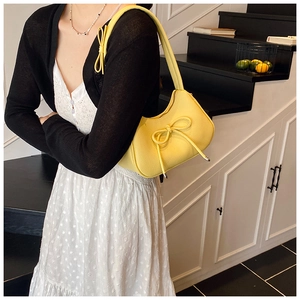 Detail of yellow bow shoulder bag with lychee texture and metallic zipper closure