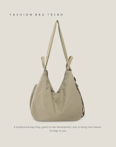Detail view of khaki nylon crescent shoulder bag featuring wide fabric strap and zip accents