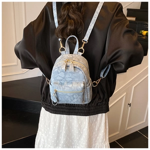 Detailed back view of a light blue floral mini backpack with adjustable gold hardware