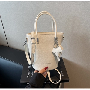 Detail of white bucket bag with pebble leather texture and a cute elephant charm