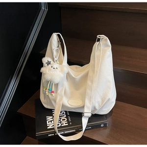 Close-up of white canvas hobo bag with square texture and a plush star charm detail