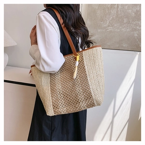 Close-up of woven tote bag with leather strap and decorative yellow tassel detail