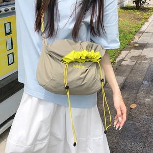 Detail of nylon drawstring crossbody bag with contrast yellow lining and beaut embroidery
