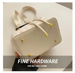 Close-up of golden hardware studs and embossed leather texture on cream backpack base