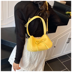 Detail of yellow bow shoulder bag showing pebbled leather texture and silver accents
