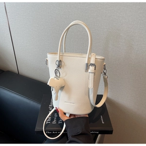 Close-up of white lychee pattern bucket bag with cute elephant charm and adjustable strap