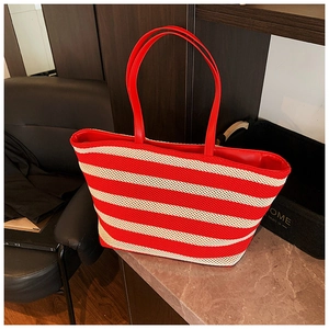 Dettaglio della borsa tote intrecciata a righe bianche e rosse con manici in pelle