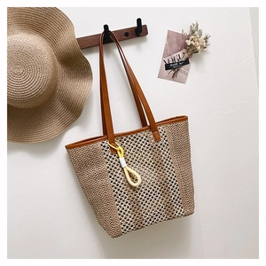 Macro view of woven straw beach tote bag showing leather strap and detailed knit pattern
