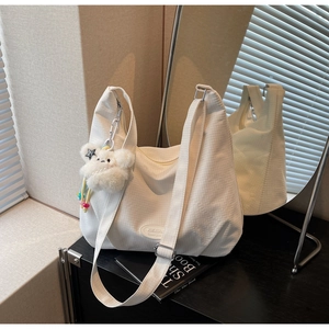 Close-up of white waffle texture tote bag with plush cloud charm and adjustable strap