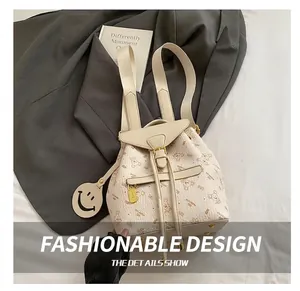 Detail of beige backpack featuring cartoon bear patterns and a yellow smiley face charm