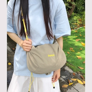 Macro detail of khaki nylon crossbody bag with yellow drawstring and beaut lettering