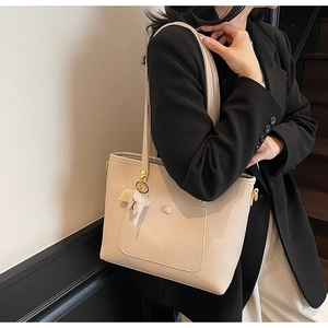 Close-up of beige lychee grain tote bag with decorative white elephant leather charm