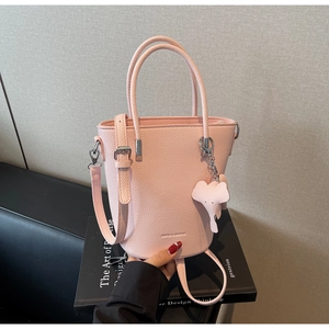 Close-up of pink pebbled leather bucket bag with cute elephant charm and adjustable strap