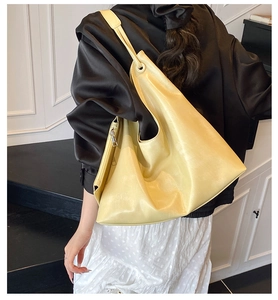 Detailed side view of large soft yellow PU leather hobo tote bag on a model's shoulder