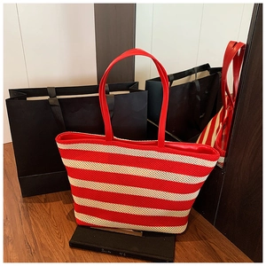 Dettaglio della borsa tote intrecciata rossa e crema con texture e manici in pelle