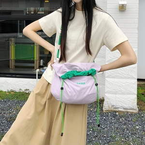 Detail of light purple nylon crossbody bag with green contrast drawstring and embroidery