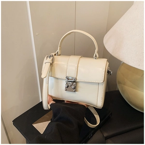 Detailed view of cream square crossbody bag featuring polished silver metal swivel lock
