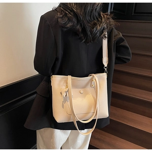 Detail of beige lychee pattern PU leather tote with wide shoulder strap and cat tag
