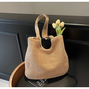 Detail of beige woven tote bag with light brown faux leather handle on wooden chair