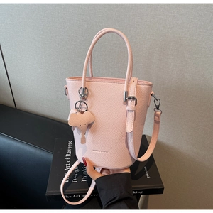 Detail of light pink pebble leather bucket bag with cute elephant charm and hand straps
