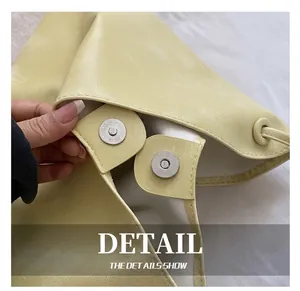 Close-up of a pale yellow bucket bag featuring a cylindrical magnetic metal clasp detail