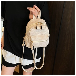 Detail of beige mini backpack with embossed floral patterns and golden hardware