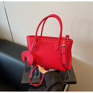 Detail of red lychee pattern leather tote bag with elephant charm and shoulder strap