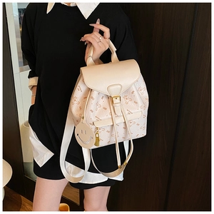 Close-up of cream backpack with bear print and cute smiley face pendant charm