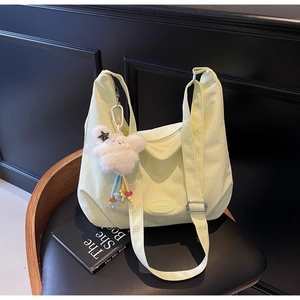 Close-up of light green plaid canvas hobo bag with adjustable strap and plush cloud charm