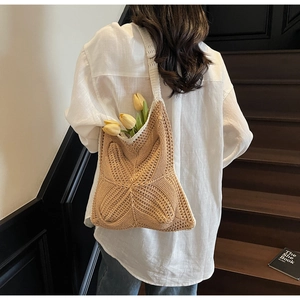 Detail of beige crochet cotton shoulder bag with hollow knit patterns and fringe accents