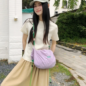 Detail of light purple nylon crossbody bag with green drawstrings and beaut embroidery