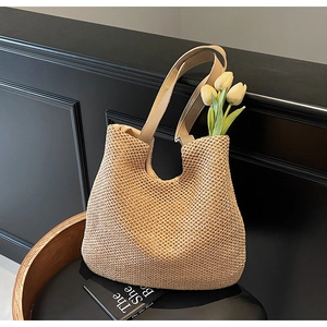 Detail of light beige woven tote bag featuring smooth synthetic leather shoulder straps