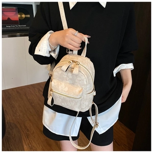 Detailed close-up of a mini cream-colored floral backpack with golden hardware and straps