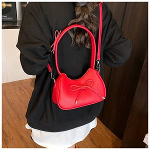 Detailed view of red bow shoulder bag with lychee texture leather on black hoodie background