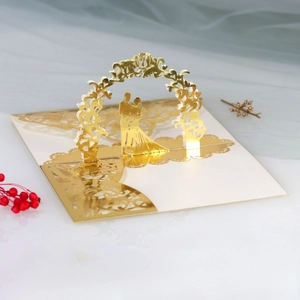 Detail of 3D laser-cut golden wedding invitation with bride and groom silhouette under arch