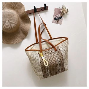 Detail of hand-woven straw tote bag with vertical stripes and leather shoulder straps