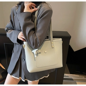 Close-up of a light sage green pebbled leather tote bag with a cute elephant charm