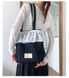 Detail of canvas shoulder bag with polka dot lace ruffle and motivational pink patch
