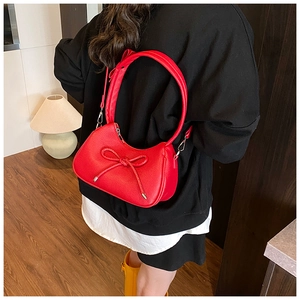 Detailed view of a red crescent bag with leather bow knot shown in a lifestyle setting