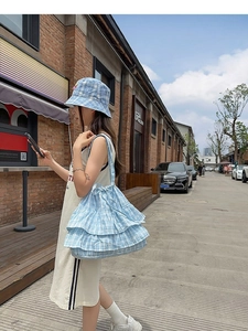 Blue and white plaid ruffle tote bag with matching bucket hat in outdoor street setting