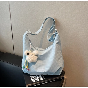 Detail of light blue checkered canvas hobo bag with cute plush rabbit charm and star strap