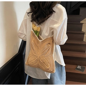 Detail of crochet tote bag with 3D butterfly relief and woven texture on model