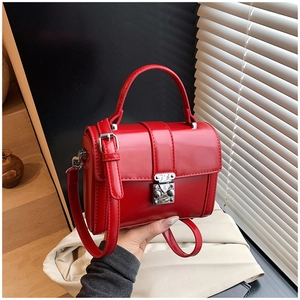 Macro shot of glossy red leather square bag with silver metal buckle and top handle